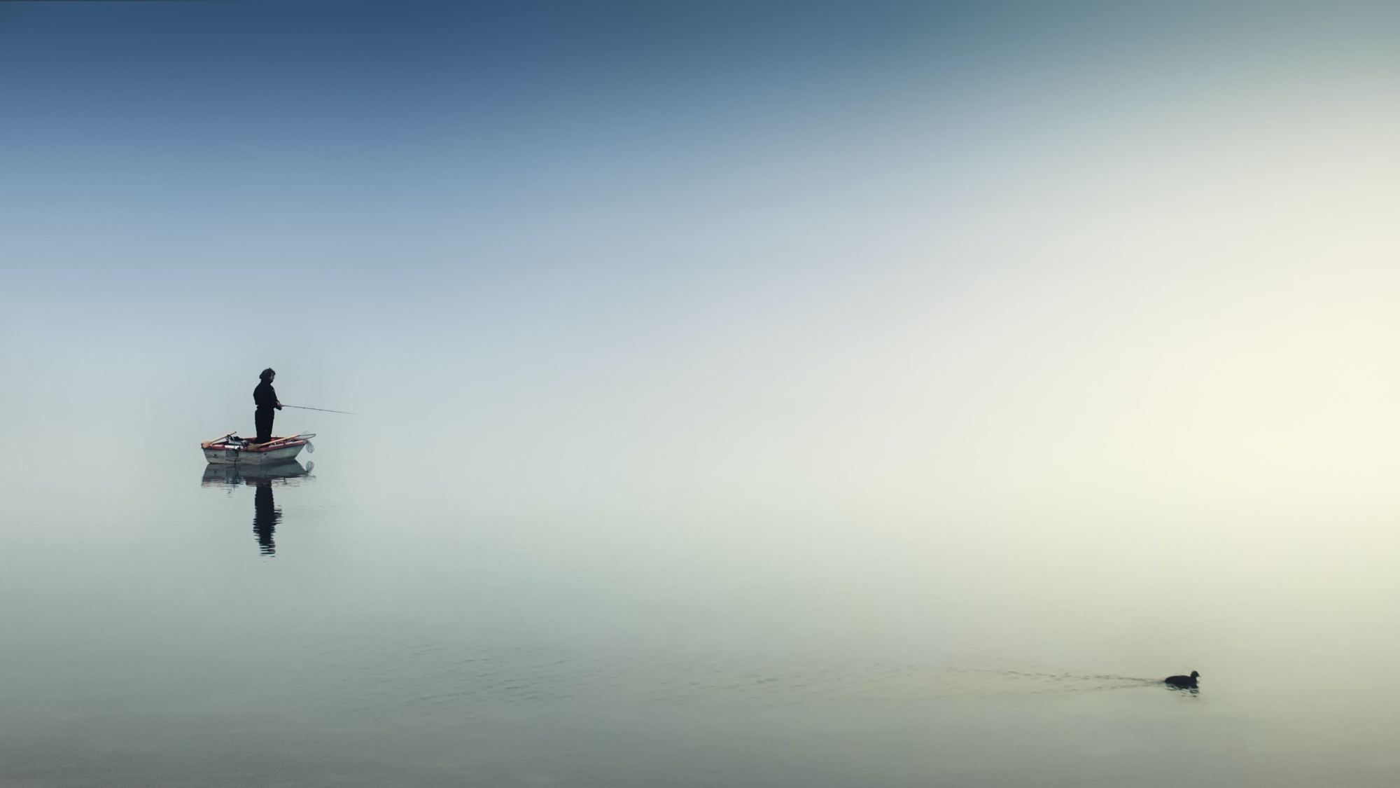 Petit bateau seul au milieu d’une mer brumeuse